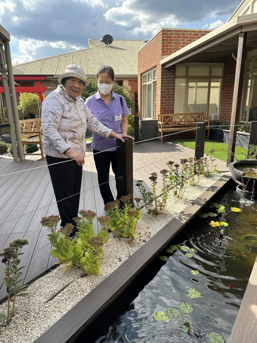 Two people looking at fish in pond.