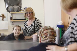 A resident and a hairdresser are looking at the mirror