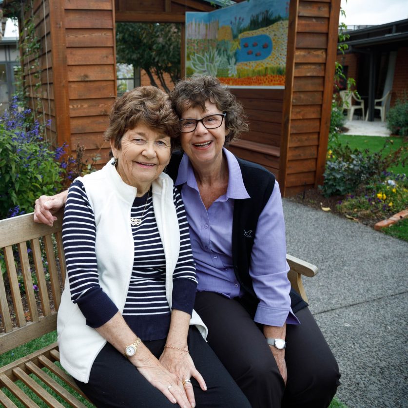 Resident and staff member sitting together in garden.