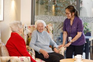 A staff member chats with two residents in the lounge area