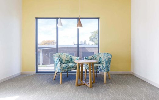 Seating area captured in front of a light yellow wall and a window