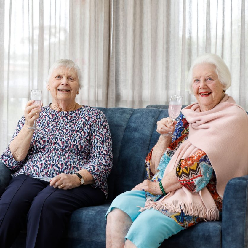Two residents enjoying a glass of bubbles in the lounge.