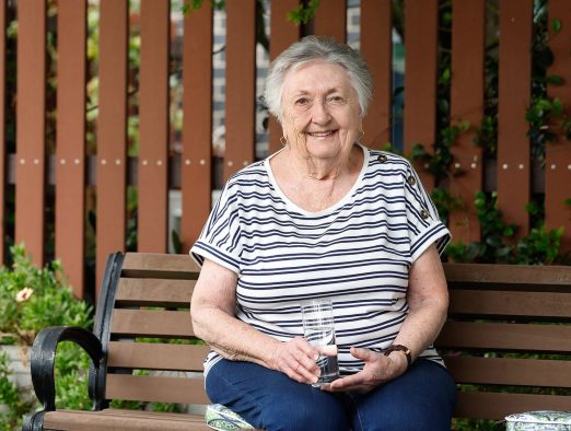 Resident sitting on bench in courtyard.