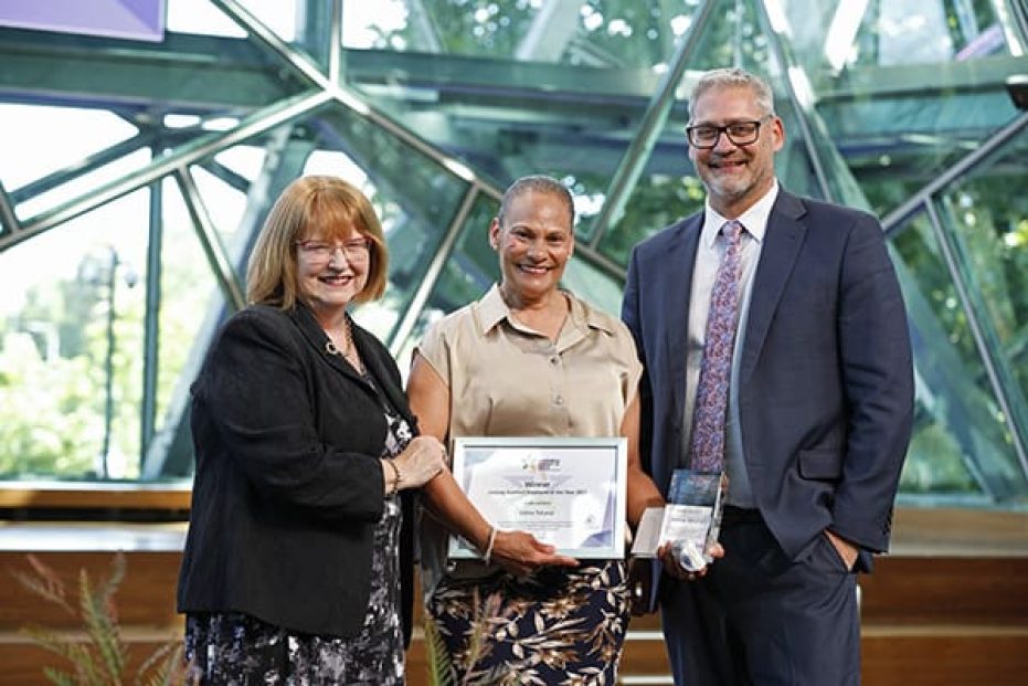 Three people with certificate on stage.
